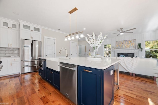 kitchen with blue cabinets, ceiling fan, a sink, and stainless steel appliances