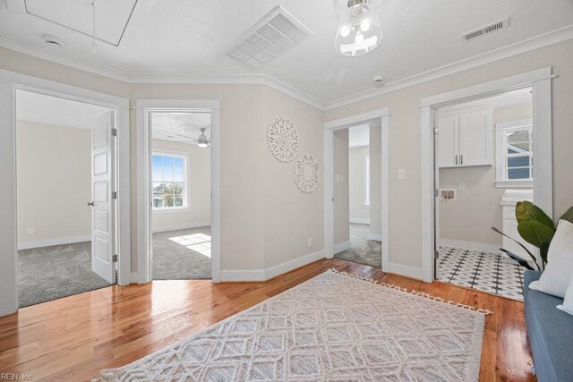 entrance foyer featuring ornamental molding, visible vents, baseboards, and wood finished floors