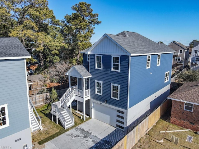 view of home's exterior with an attached garage, board and batten siding, stairway, concrete driveway, and roof with shingles