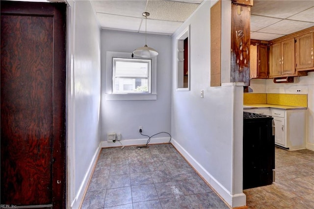 kitchen with light countertops, light tile patterned floors, decorative light fixtures, baseboards, and a paneled ceiling