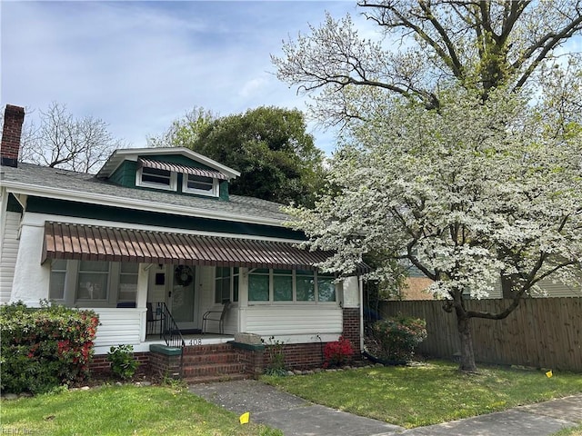 bungalow featuring a shingled roof, a front lawn, fence, and covered porch