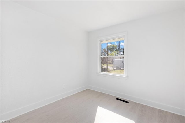 empty room featuring light wood finished floors, visible vents, and baseboards