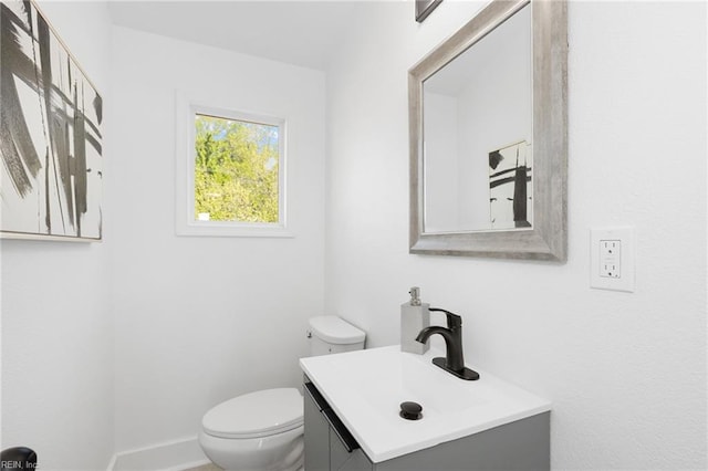 half bath featuring toilet, vanity, and baseboards