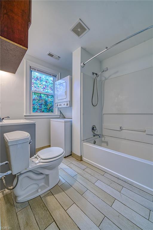 217 Hurley Ave, Newport News, VA 23601 - bathroom with visible vents, toilet, stacked washer / dryer, and wood tiled floor