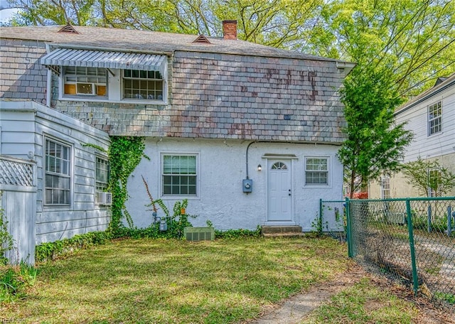 217 Hurley Ave, Newport News, VA 23601 - view of front facade featuring stucco siding, a chimney, mansard roof, a front lawn, and fence