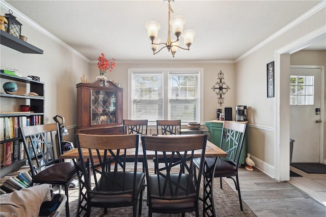 dining space with light wood-type flooring, an inviting chandelier, crown molding, and baseboards