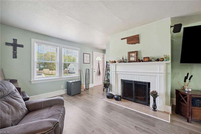 living area with wood finished floors, baseboards, and a brick fireplace