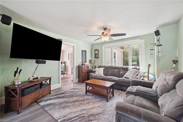 living room featuring light wood finished floors, baseboards, and a ceiling fan