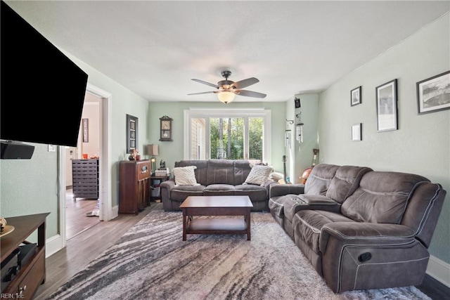 living room with baseboards, a ceiling fan, and wood finished floors