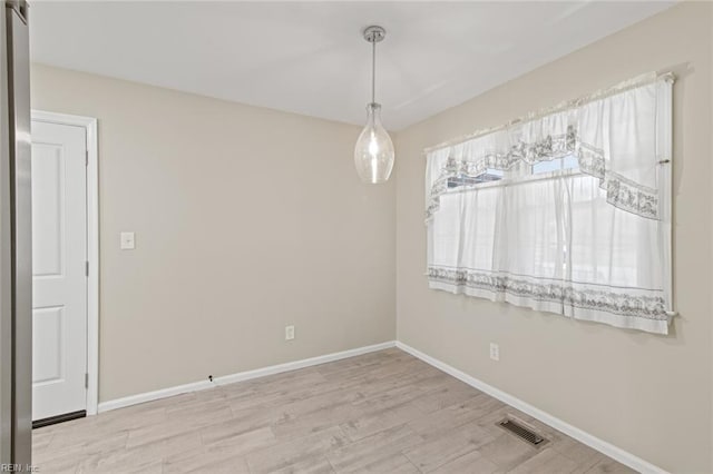 empty room featuring wood finished floors, baseboards, and visible vents