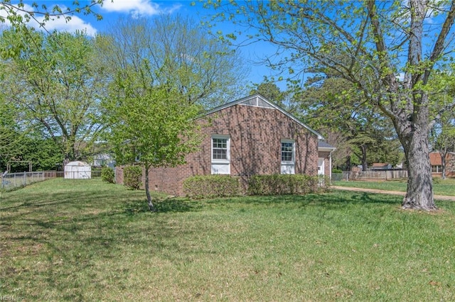view of side of property with a yard, brick siding, and fence