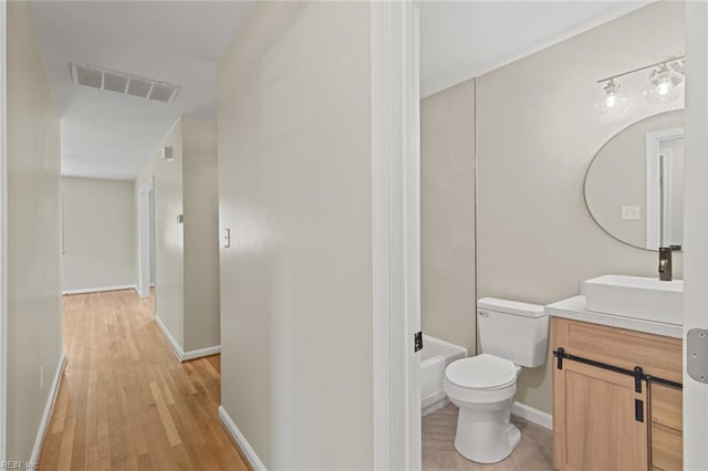 bathroom featuring visible vents, baseboards, toilet, vanity, and wood finished floors