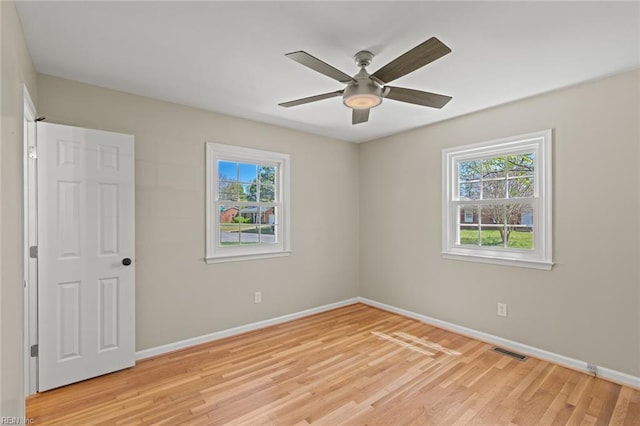 unfurnished room featuring light wood-type flooring, a healthy amount of sunlight, baseboards, and visible vents