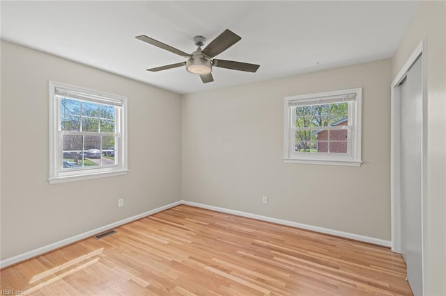 unfurnished bedroom with a closet, baseboards, ceiling fan, and light wood-style floors