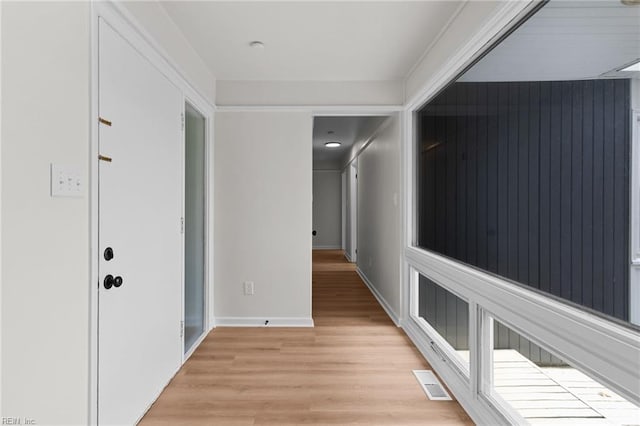 hall with visible vents, baseboards, and light wood-type flooring
