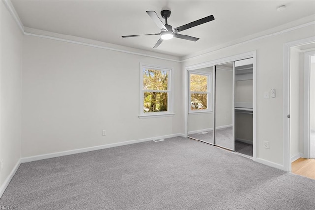 unfurnished bedroom with ceiling fan, carpet, a closet, ornamental molding, and baseboards