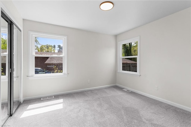 unfurnished room with light carpet, visible vents, and baseboards