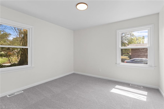 carpeted empty room featuring visible vents and baseboards