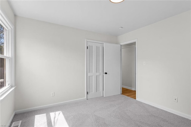 unfurnished bedroom featuring carpet, visible vents, a closet, and baseboards