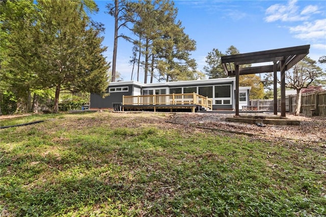 rear view of property featuring fence, a deck, a sunroom, and a lawn