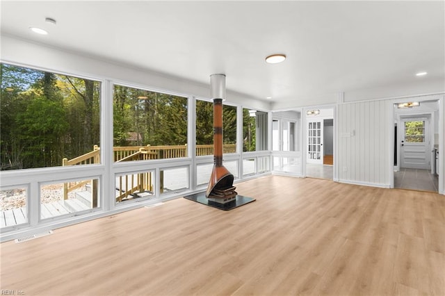 unfurnished living room featuring light wood finished floors, a wood stove, visible vents, and recessed lighting