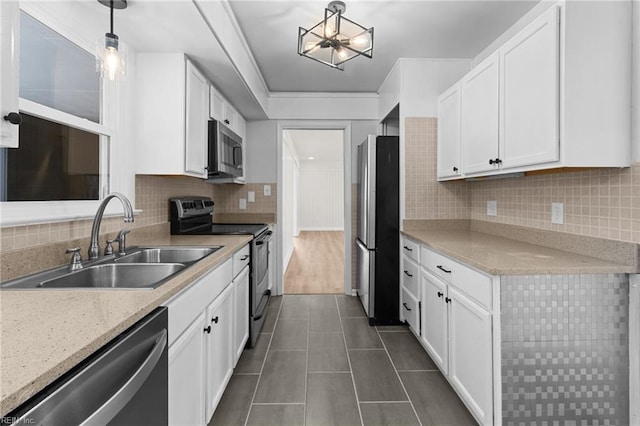 kitchen featuring white cabinets, a sink, appliances with stainless steel finishes, dark tile patterned flooring, and backsplash