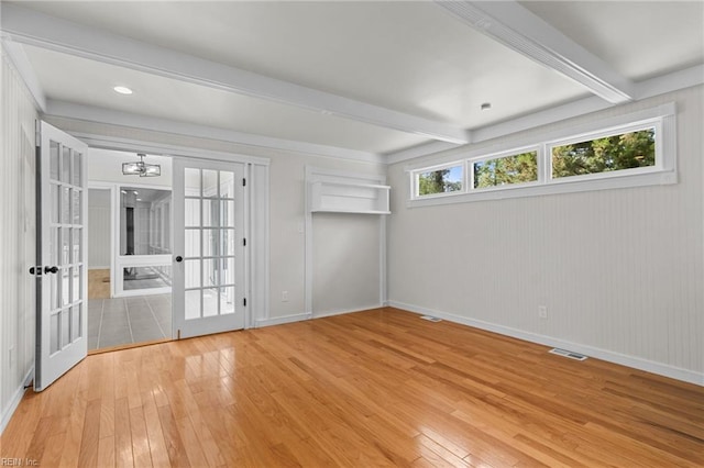 spare room featuring light wood-type flooring, visible vents, a chandelier, french doors, and beam ceiling