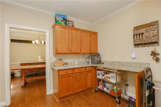 kitchen featuring light stone counters, an inviting chandelier, ornamental molding, and wood finished floors