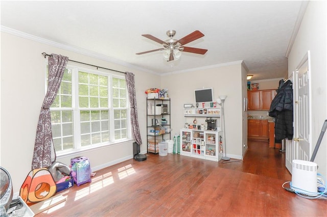 recreation room with ceiling fan, baseboards, ornamental molding, and wood finished floors