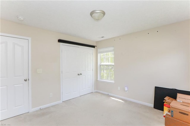 unfurnished bedroom featuring light colored carpet, baseboards, and a closet