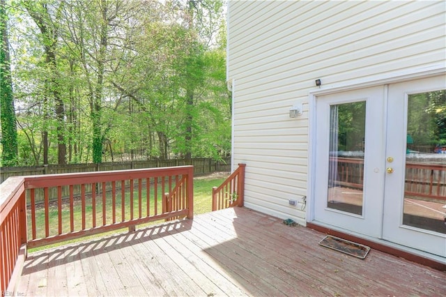 wooden terrace featuring french doors, a lawn, and a fenced backyard