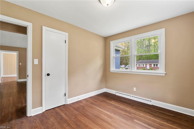 spare room with wood finished floors, a baseboard heating unit, and baseboards