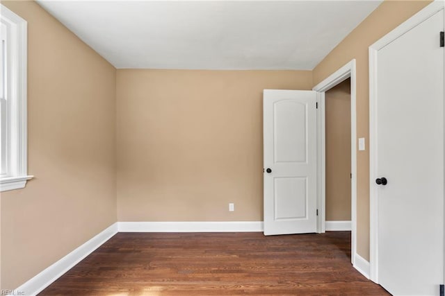 spare room featuring dark wood-style flooring and baseboards