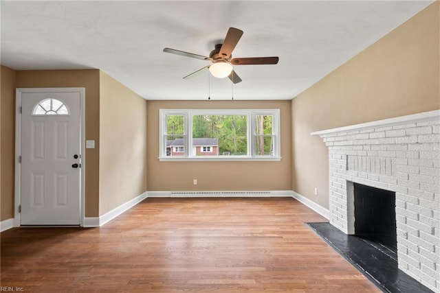 unfurnished living room with wood finished floors, a baseboard heating unit, baseboards, and a ceiling fan