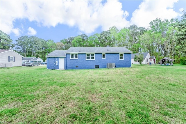 back of property with central air condition unit and a lawn