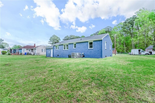 rear view of property featuring brick siding, a lawn, and central air condition unit