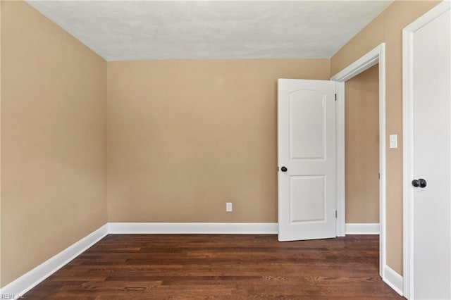 unfurnished room featuring dark wood-style floors and baseboards