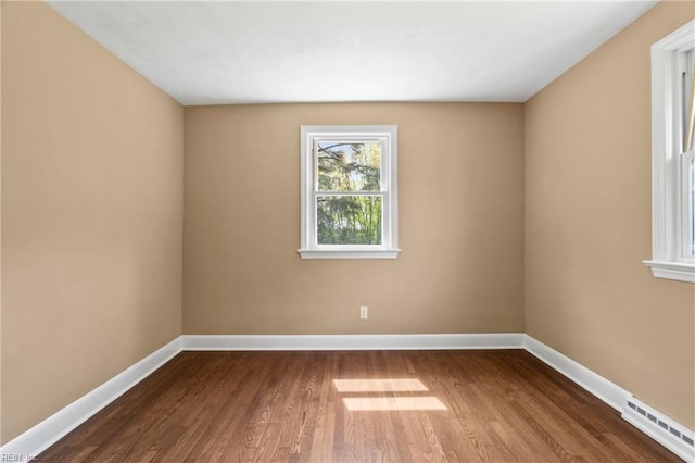 unfurnished room featuring visible vents, baseboards, and wood finished floors