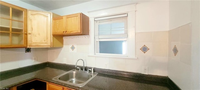 kitchen with a sink, glass insert cabinets, and dark countertops
