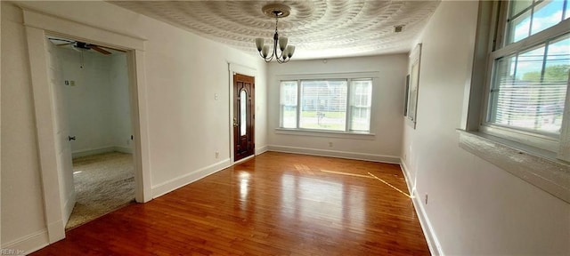 spare room featuring baseboards, a chandelier, and wood finished floors