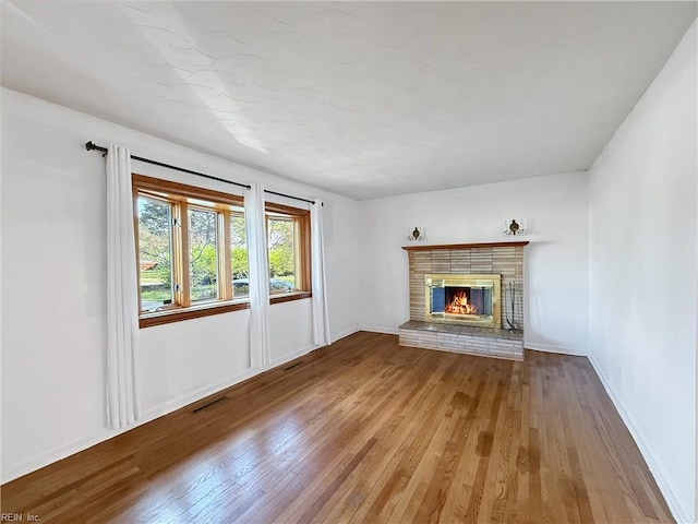 1279 Old Buckroe Rd, Hampton, VA 23663 - unfurnished living room with wood-type flooring, visible vents, baseboards, and a brick fireplace
