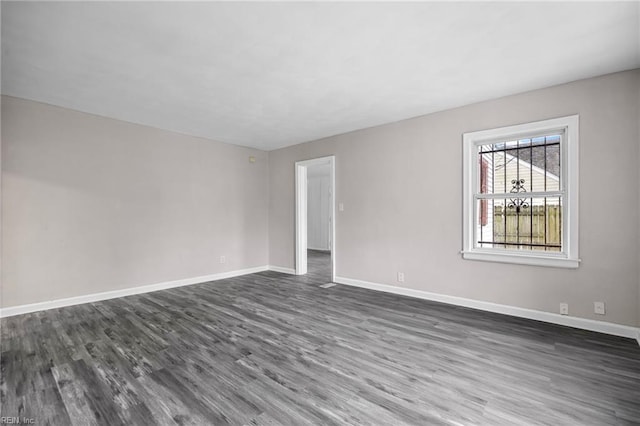 empty room with baseboards and dark wood finished floors