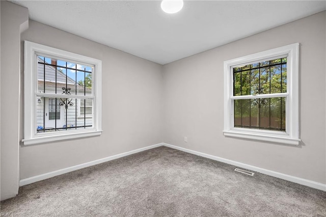 carpeted spare room with visible vents and baseboards