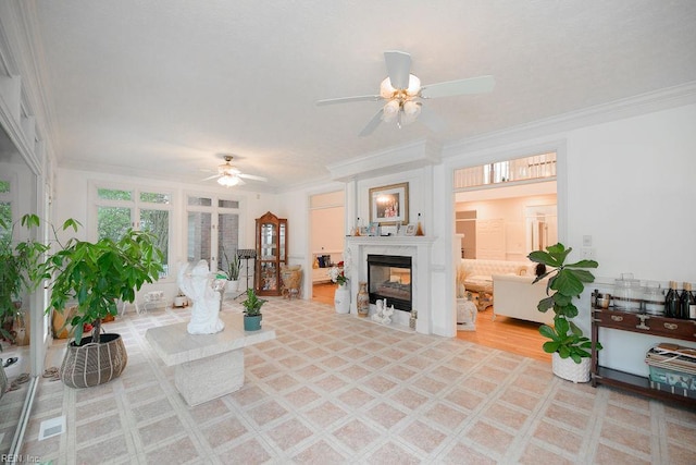 living room with a premium fireplace, crown molding, and ceiling fan