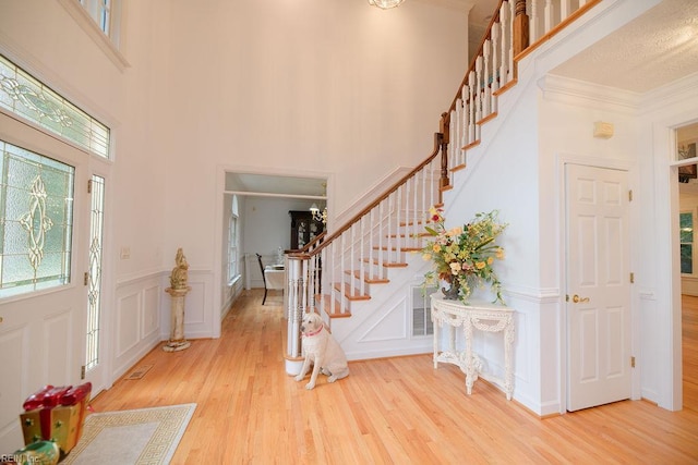 foyer entrance featuring stairs, plenty of natural light, crown molding, and wood finished floors