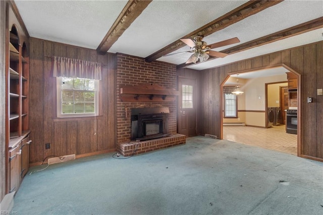 unfurnished living room featuring wood walls, plenty of natural light, and separate washer and dryer