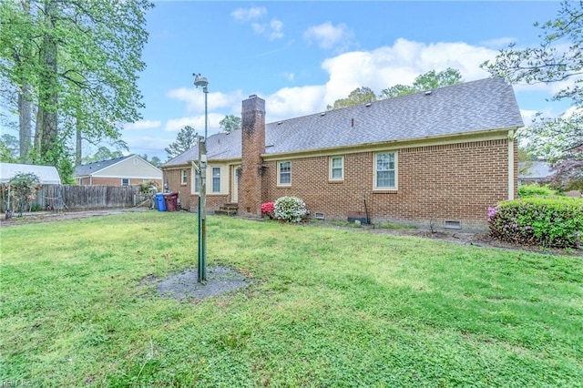 back of property featuring a chimney, brick siding, fence, and a yard