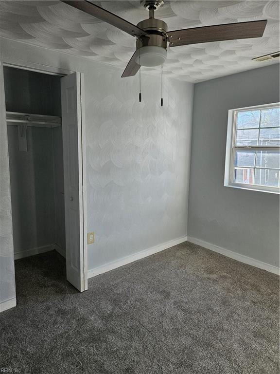 unfurnished bedroom featuring dark colored carpet, visible vents, a closet, and baseboards