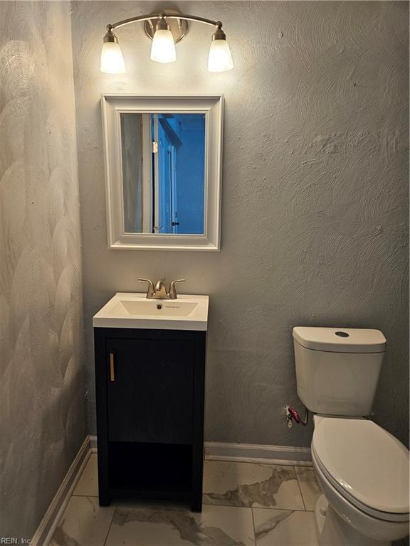 bathroom featuring vanity, marble finish floor, baseboards, and toilet