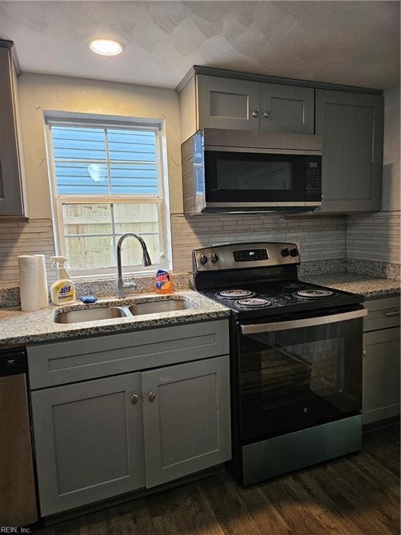 kitchen with stainless steel appliances, dark wood finished floors, a sink, and gray cabinets